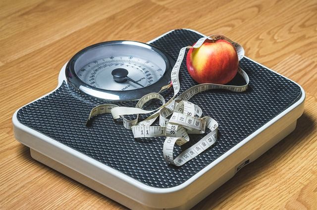Represents New Years Eve Resolutions with a scale, measuring tape, and an apple